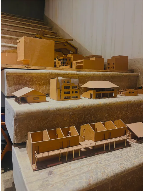 Architectural models in cardboard on wooden steps.